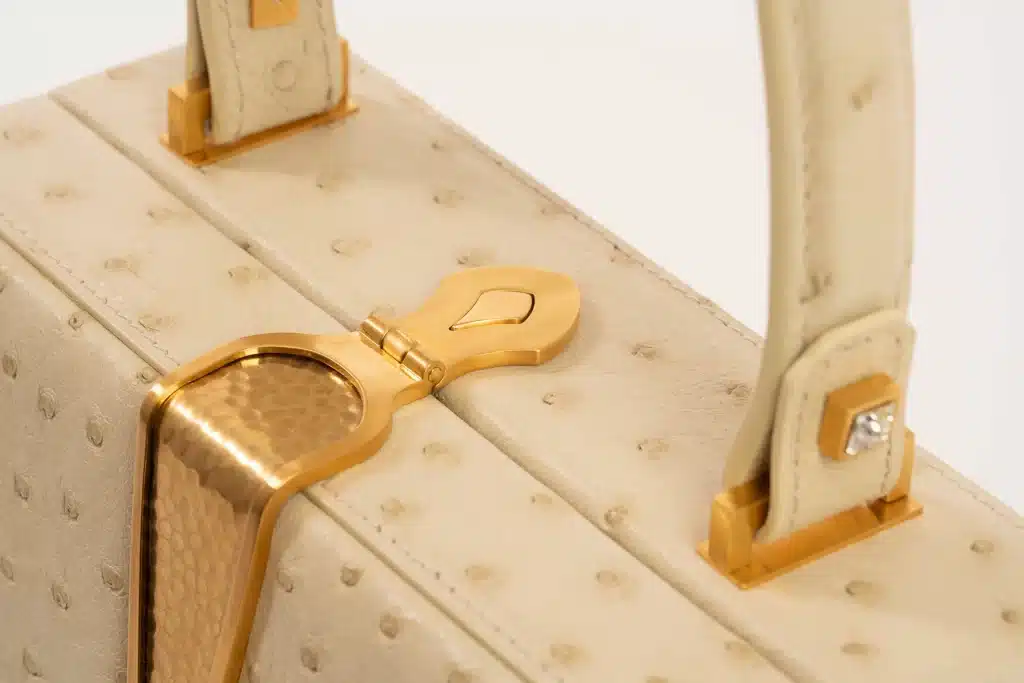 Dettaglio della chiusura metallica dorata, simbolo del brand Rivelia