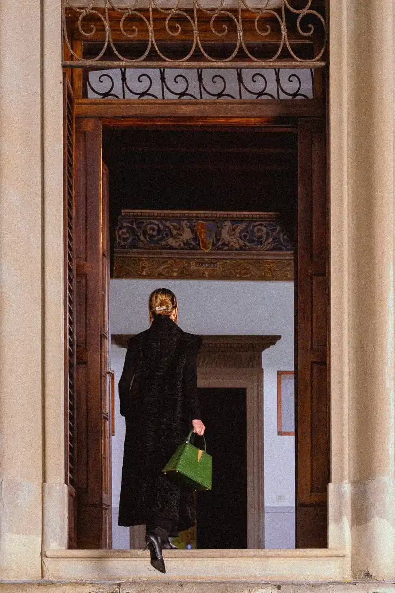 Dettaglio di stile, borsa artigianale indossata sulle scalinate di un palazzo storico